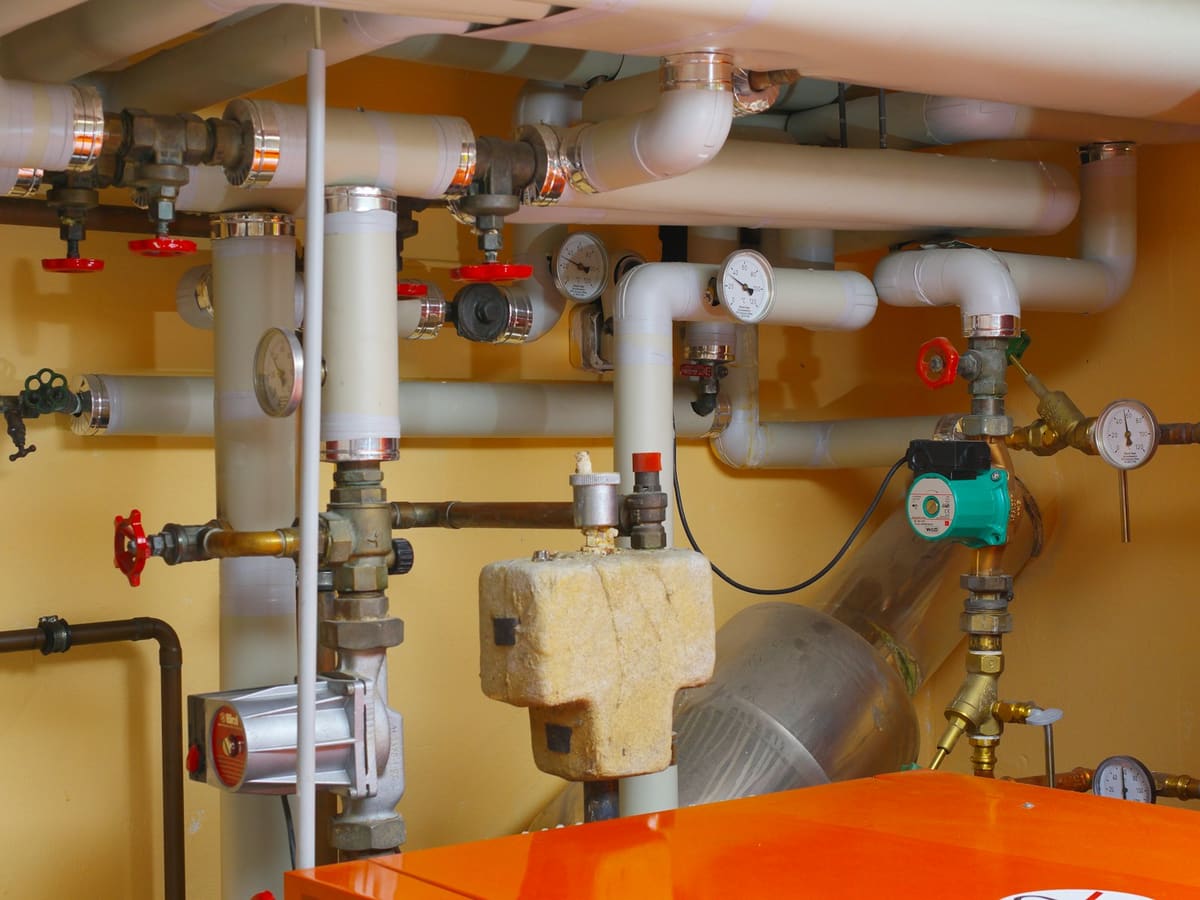 Heating plant room with pressure gauges, safety valves, a circulating pump and an expansion vessel